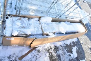 Cardboard box containing Hoshizaki HNC-210BA-L-SLH sushi display case with snow on top, partially visible. Box shows wear.