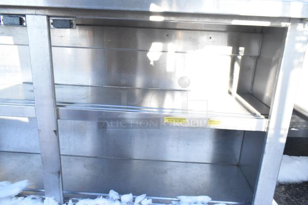 Stainless steel counter with two under shelves, labels reading "Food Processor Accessories" and "Immersion Blender", in good condition.