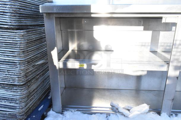 Stainless steel counter with two under shelves, in good condition, features labeled for scales. Sturdy construction for kitchen use.