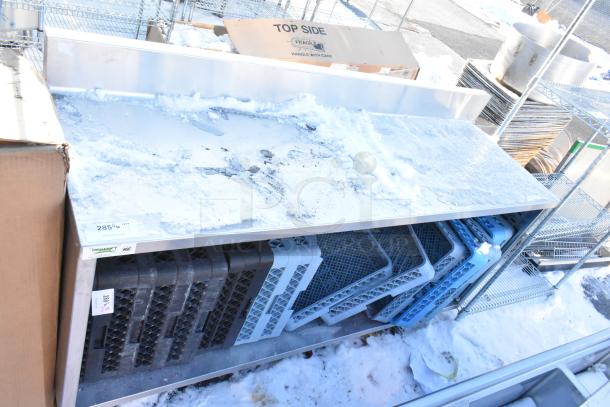 Regency 600EBTB2472 stainless steel table with snow-covered surface, enclosed base, midshelf, 6" backsplash, and dish caddies.