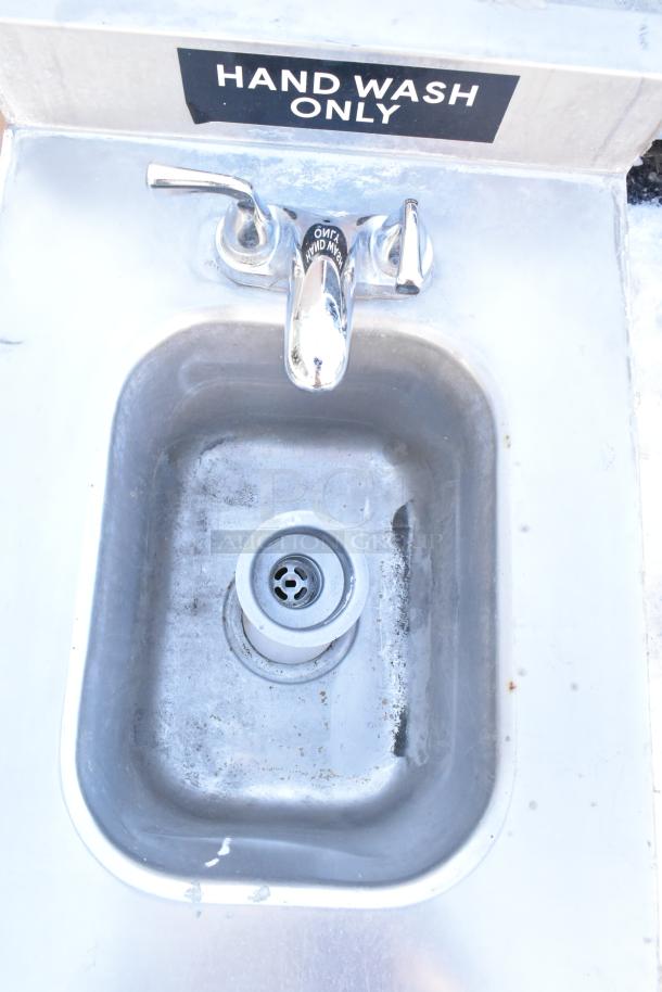 Stainless steel single bay sink, no legs, "Hand Wash Only" label, moderate wear visible, includes faucet and drain.