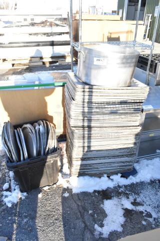 Stack of metal full-size baking pans, metal stock pot, and stock pot lids on display outdoors. 100 times your bid offer.