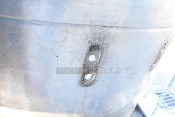 Metal stock pot with visible wear and attachment points, part of a lot including baking pans and lids. Auction item: 100 items.