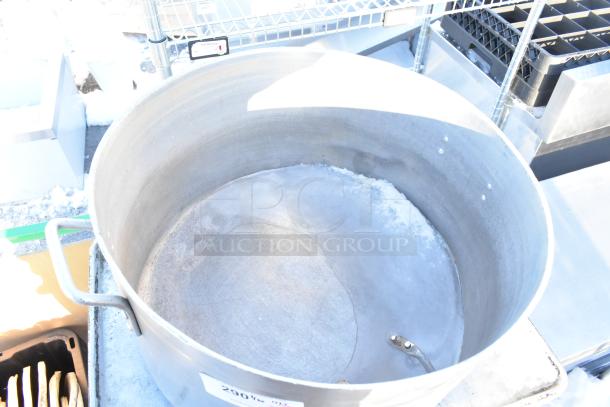 Large metal stock pot with handles, showing some signs of wear. Auction lot includes baking pans and lids.