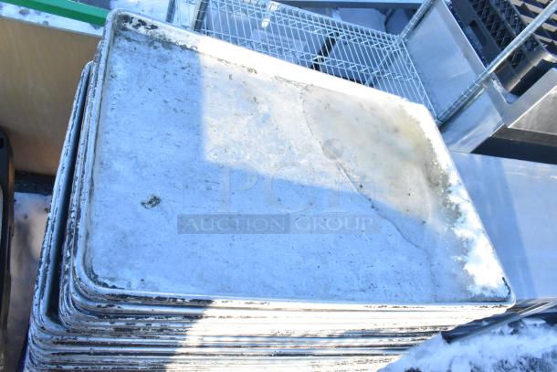Stack of metal full-size baking pans with visible wear and discoloration, auctioned as part of 100 kitchen items.