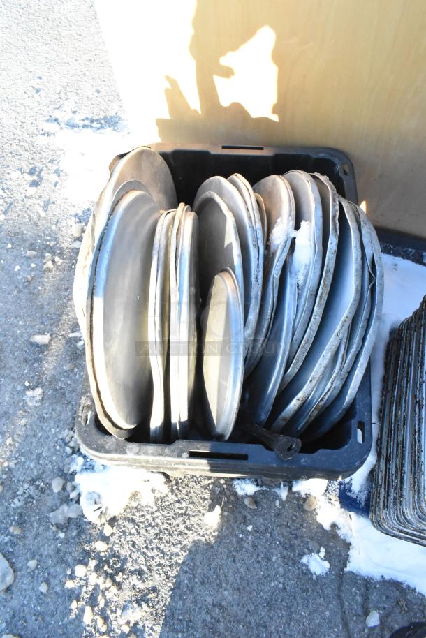 Stack of metal baking pans in a crate. Used condition, visible wear. Includes various full-size pans, stock pot lids.