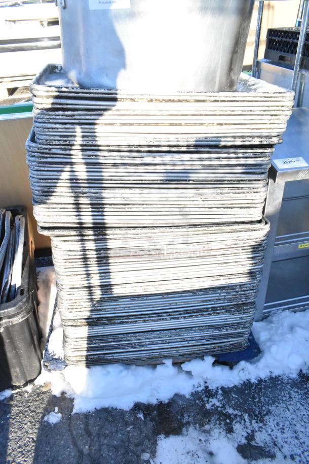 Stacked metal baking pans and stock pot in used condition on snow-covered ground, auction label visible.