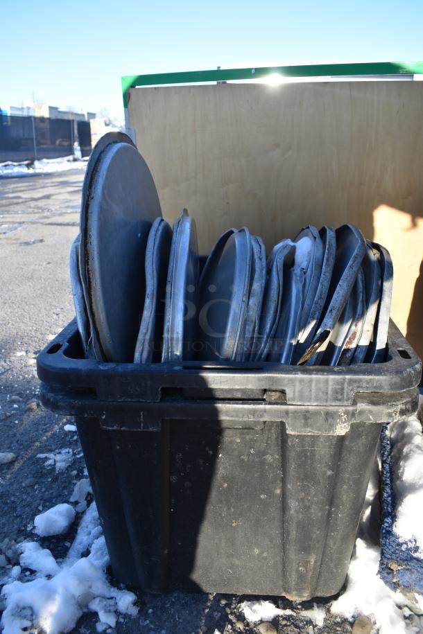 Black bin filled with various metal items, including full-size baking pans and stock pot lids, showing signs of wear.