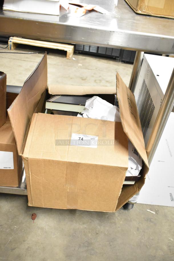 Box containing approximately 25 items, including notebooks, copy paper reams, and a Lexmark printer cartridge, labeled "74 QTY".