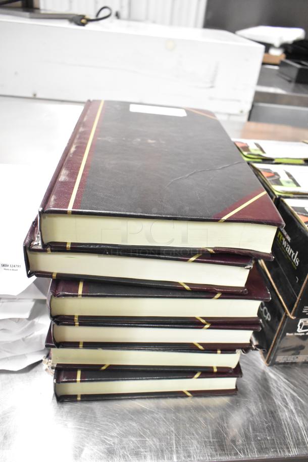 Lot of approximately 25 items including stacked notebooks with maroon covers, copy paper reams, Lexmark printer cartridge visible.