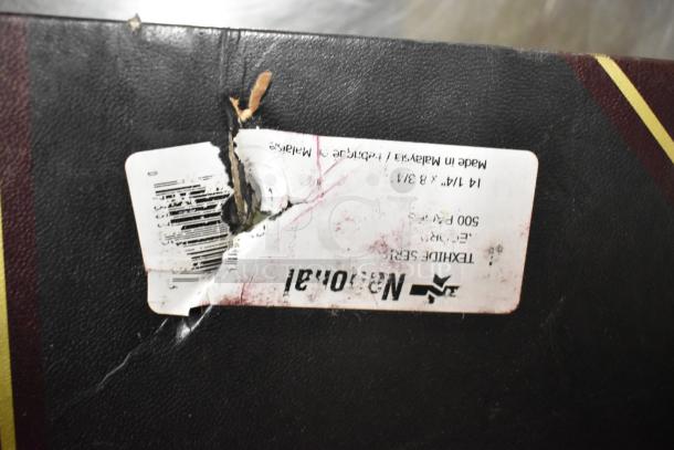 Damaged label on a black notebook cover with a torn area revealing cardboard underneath. Label includes size and "Made in Malaysia."