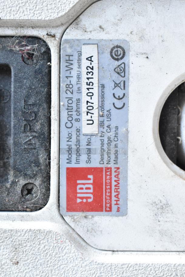 Close-up of JBL Control 28-1-WH speaker label, showing model number, 8 Ohm impedance, and serial number U-707-015132-A.