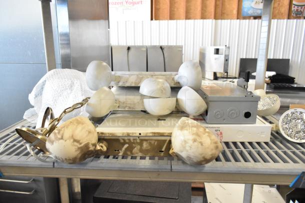 19 assorted items including emergency lights, exit sign, and Eaton power box in used condition, displayed on a metal rack.