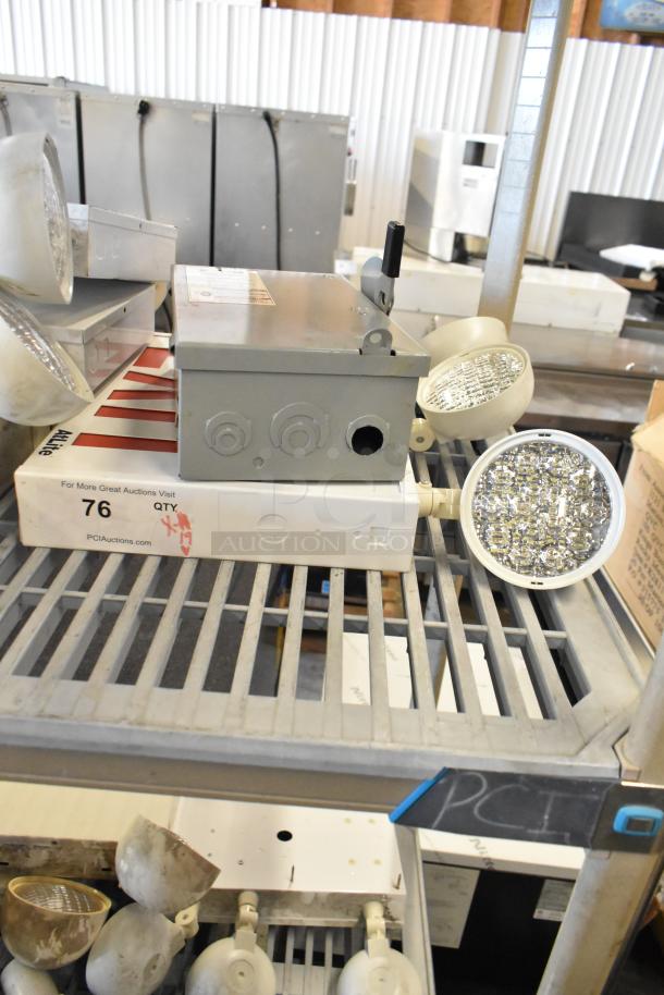 Auction lot of 19 items, including emergency lights, exit sign, Eaton power box on a metal shelf. Visible signs of wear.