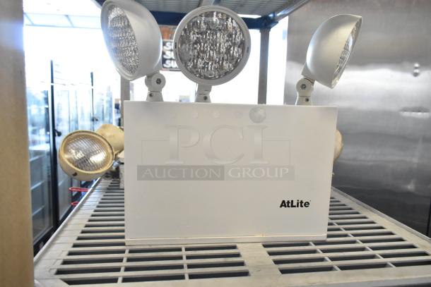 AtLite emergency light unit with dual adjustable lamps, in new condition. Model details not visible.