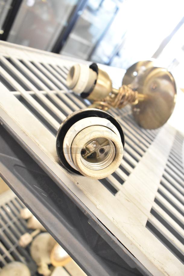 19 various electrical items including socket fixtures and brass lamps, arranged on a metal shelf. Condition varies.