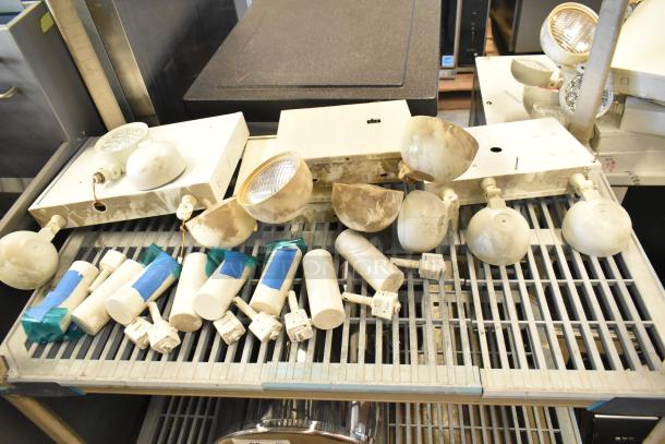 Assorted emergency lights, exit sign, and Eaton power box in used condition on a metal shelf. Includes wires and mounting bases.