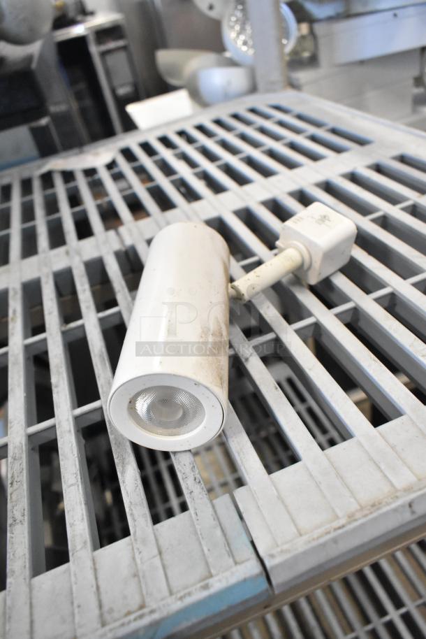 White emergency light with round lens on a metal grate. Slightly worn condition. Part of a set of 19 various items.