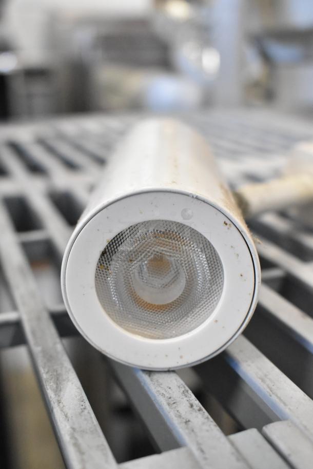 Close-up of an emergency light with a white casing and textured lens on a metal surface, showing signs of use.