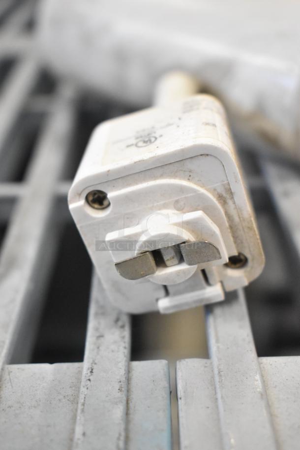 White electrical connector from a lot of 19 items, including emergency lights, exit sign, and Eaton power box. Used condition.