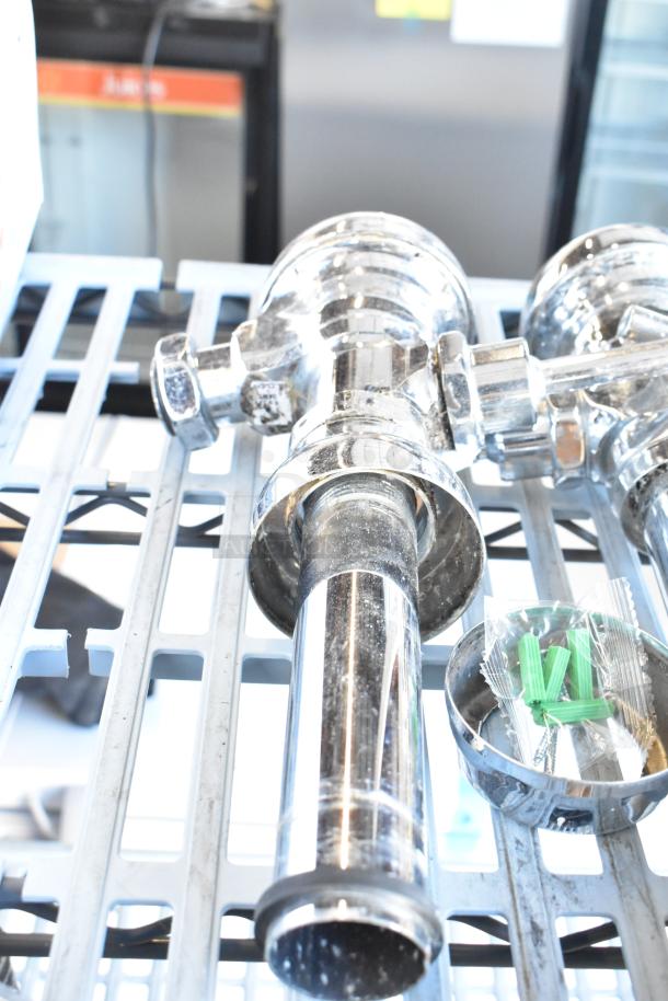 Three chrome flushing handles on display shelf, reflecting light. Includes attached green installation parts. Good condition.