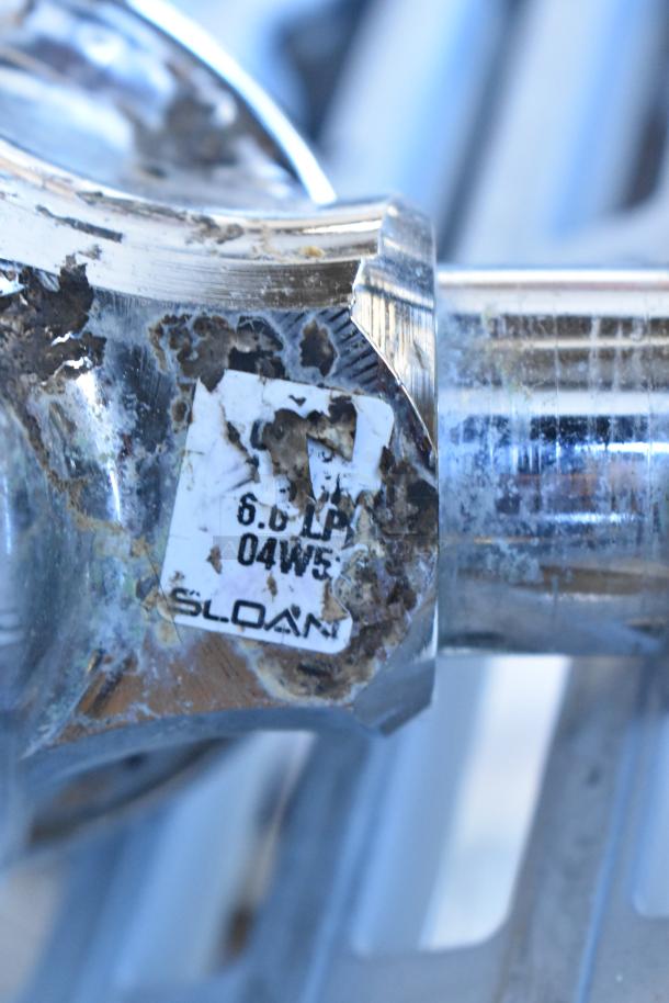 Sloan flushing handle with visible wear, labeled "6.0 LP 04W5." Chrome finish, condition suggests prior use.