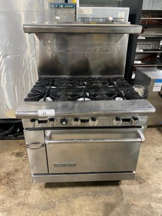 American Range stainless steel gas-powered 6-burner range/oven combo with backsplash, overhead salamander shelf, and wired oven rack.