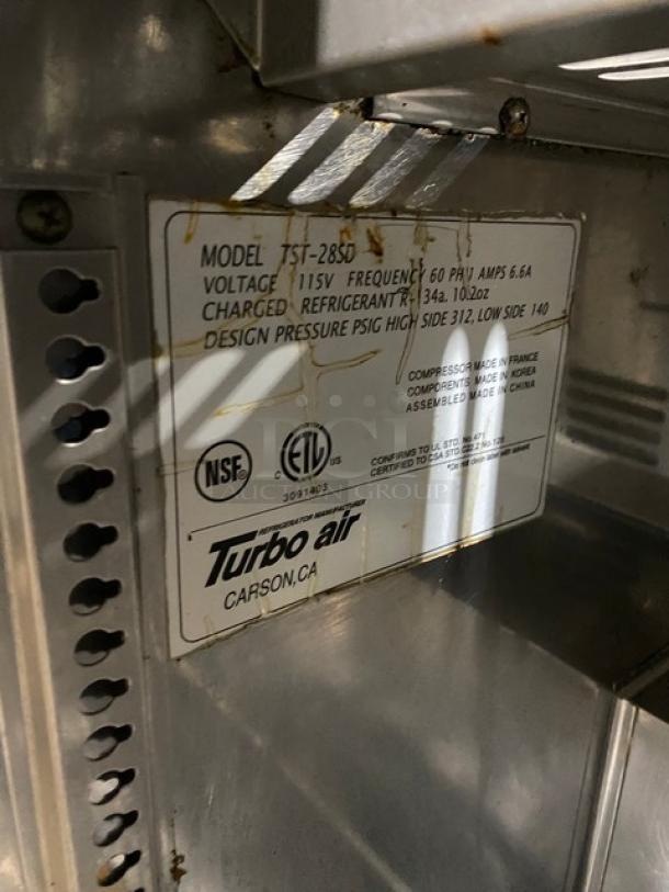 Turbo Air TST-28SD stainless steel prep table, 115V. Features include a cutting board and casters. Model label visible.