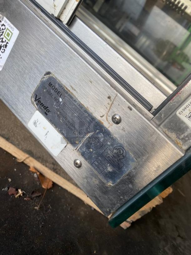 Vendo stainless steel heated food merchandiser, slanted glass, multi-tier, rear sliding doors, 115V, model label visible.