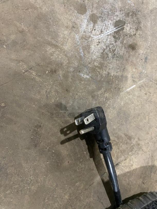 Close-up of a plug for a Continental SW3212M refrigerated prep table on a concrete floor.