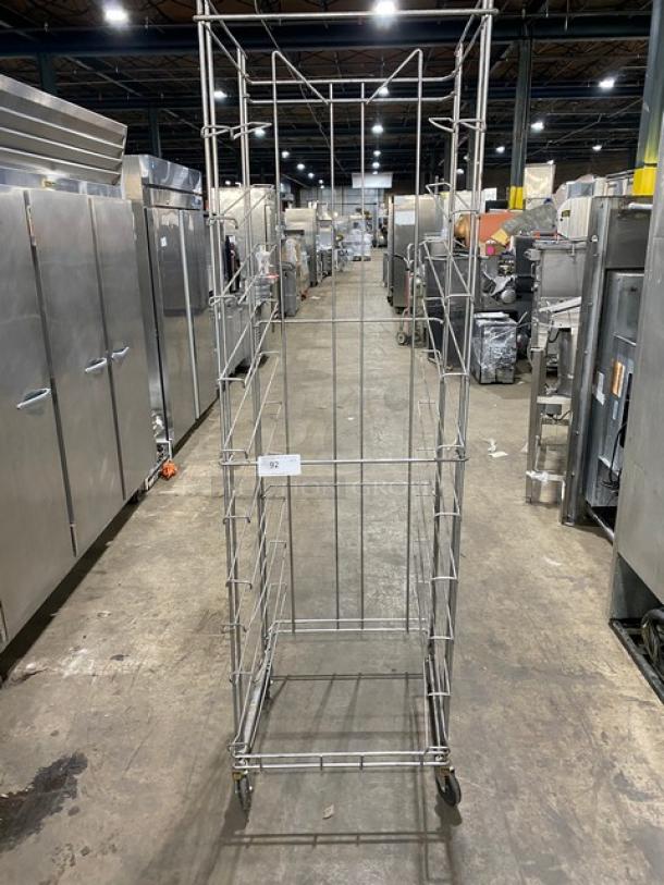 Steel flat wire bread rack on casters, commercial-grade, tall and narrow, used condition, industrial setting.
