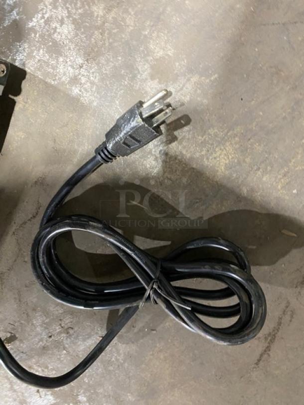 Power cord for Maxx Ice Commercial Ice Maker, Model MIM50. Standard plug on a concrete floor, coiled and secured.