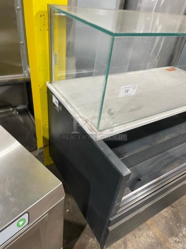 Structural Concepts black multi-level refrigerated display case with upper glass showcase, on legs, good condition.