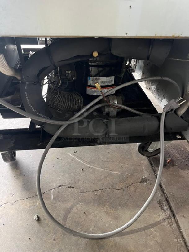 Beverage-Air KF241AS commercial freezer base, showing compressor, wiring, and casters. Plug and cables visible.