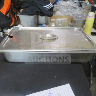 Stainless steel full-size hotel pan with lid, 4-inch deep, in used condition, on display with other kitchen items.