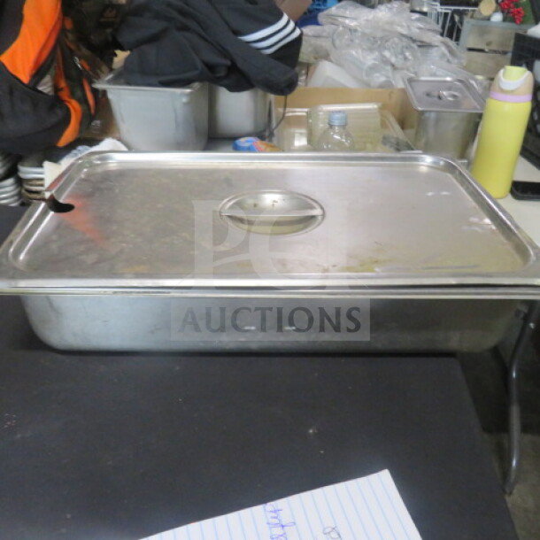 One full-size 4-inch deep stainless steel hotel pan with lid, used, minor surface wear, ideal for catering or buffet use.