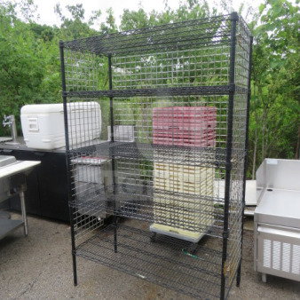 Metro shelf unit with five wire shelves, black metal, size 48x24x75 inches, outdoor setting, slightly used condition.