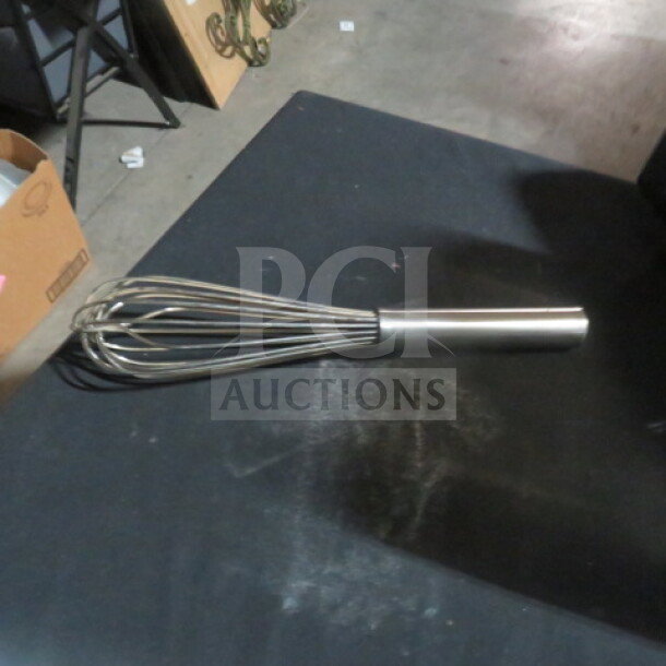 Stainless steel whip with a smooth handle, new condition, resting on a dark surface.