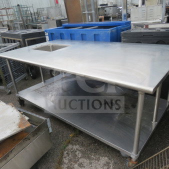 Stainless steel work table with undershelf and sink, on casters, 84x48x35 inches, in used condition.