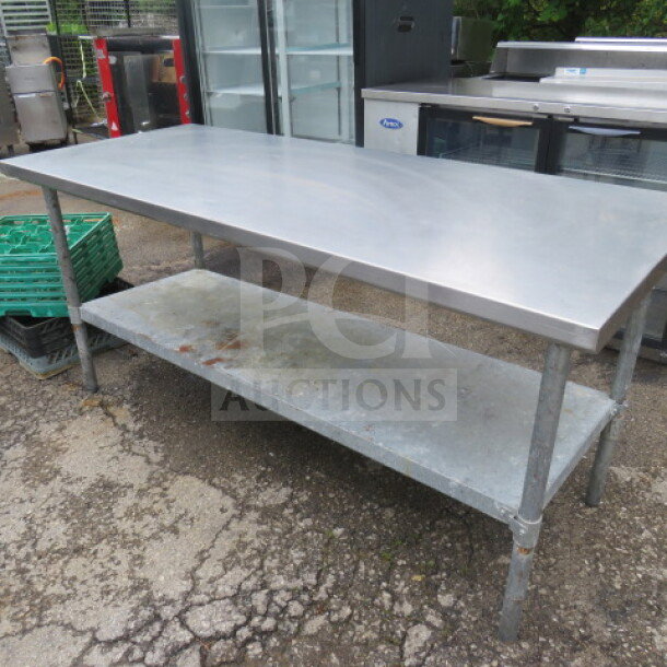 Stainless steel table with under shelf, dimensions 72x30x34 inches. Used condition, visible wear on shelf. Suitable for kitchen use.
