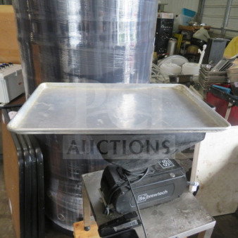 Aluminum 1/2 size sheet pan, visibly used, resting on a black piece of equipment in a workshop setting.