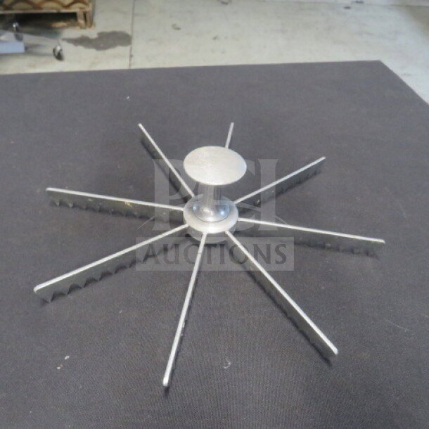 Metal pie cutter with eight serrated blades arranged in a radial pattern. Appears in good condition.
