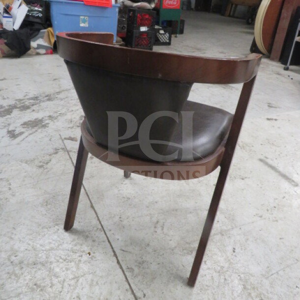 Wooden barrel back chair with cushioned seat and back, in good condition. Brown finish with black leather cushion.