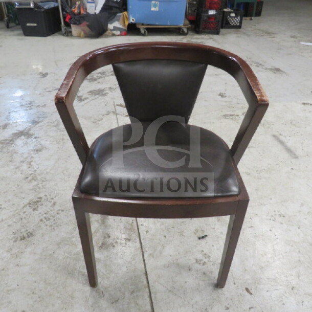 Wooden barrel back chair with cushioned seat and back. Dark wood, black leather upholstery. Good condition.