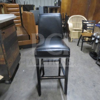 Wooden bar-height chair with black cushioned seat and back, featuring a footrest. Good condition.