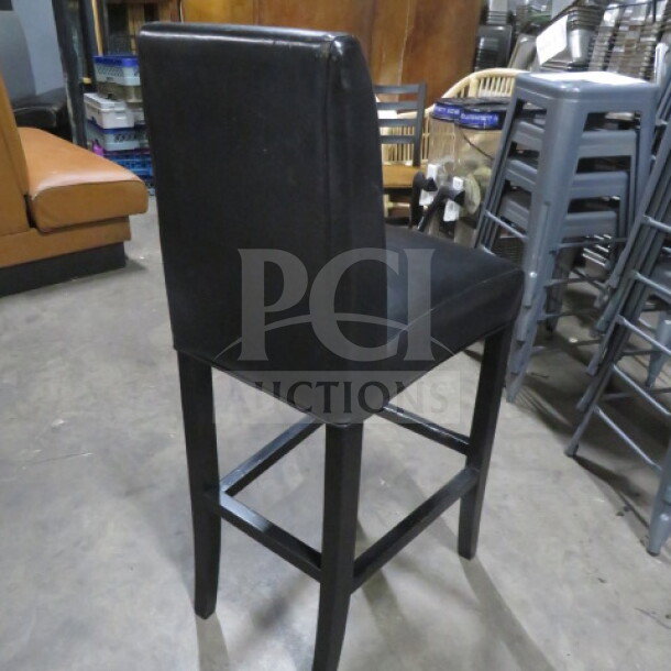Wooden bar height chair with black cushioned seat and back, featuring a footrest. Good condition.