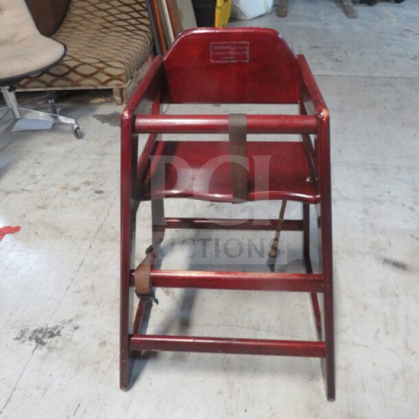 Wooden high chair with safety straps, sturdy construction, moderate wear. Suitable for toddlers. 