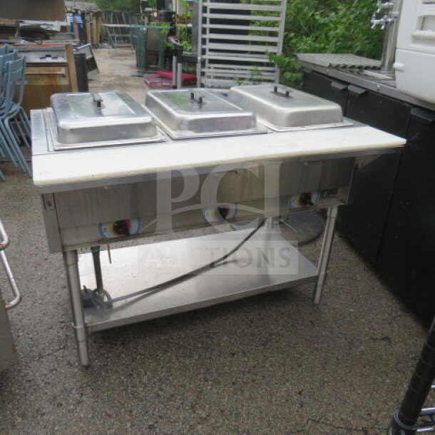 One 3 well electric steam table with stainless steel under shelf and cutting board, dimensions 46x30x34, in used condition.