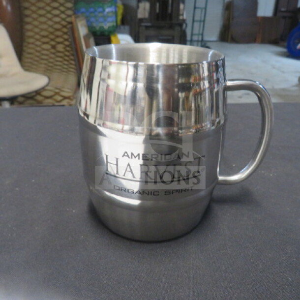 Stainless steel mug, engraved with "American Harvest Organic Spirit," featuring a sleek design and sturdy handle.