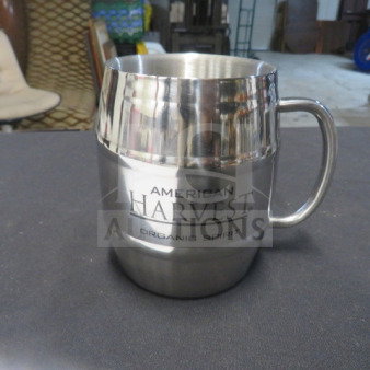 Stainless steel mug, engraved with "American Harvest Organic Spirit," featuring a sleek design and sturdy handle.